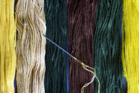 Needle with thread and set of multi-colored cotton threads. Top view. Colorful mouline threads. Set...