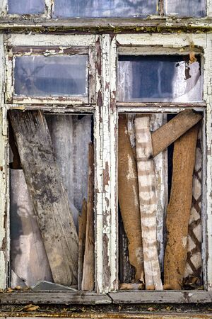 Window with broken glass boarded up with boards. Slums, poverty, devastation. Close-up. Selective...