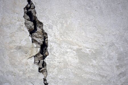 Big crack on the gray wall, abstract image of the vertical cleft. Close up. Selective focus. Copy...