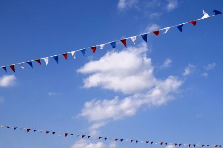 Colourful decorative triangular flags under blue sky with clouds. Sunny summer day.の写真素材
