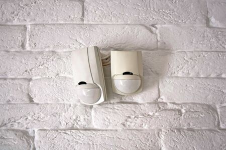 Sensors of the security system. Mounted on an old brick wall painted white. Close-up. Selective...