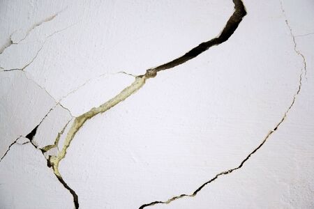 Large cracks on a white wall, abstract image of a crevice network. Selective focus. Copy space....