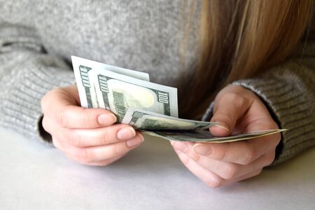 Woman's hands counting dollar banknotes. Female holding money currency of United States. Close-up....