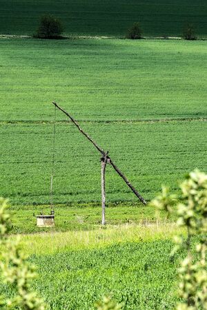 Old well located near the field road. An ancient way to extract water. Surrounded by green fields....