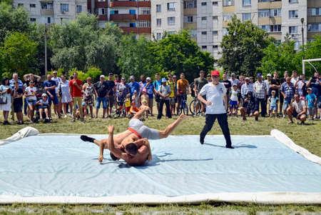 Moldova, Rybnitsa - July 2019: wrestling competition. Two young men compete in freestyle wrestling, throw. Match takes place on street sports ground.のeditorial素材