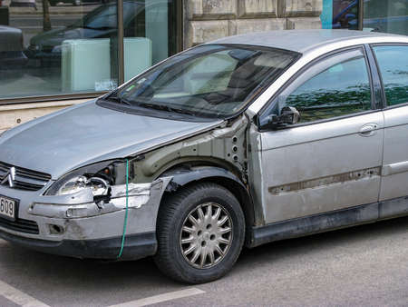 Old car after an accident. Dismantled wing, damaged mirror and front door. Color - metallic silver....