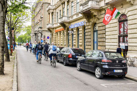 Group of tourists cyclists with backpacks travels through the old city. Back view. Cityscape. Close-up. Selective focus. Copy space. Hungary, Budapest - may 2019.のeditorial素材