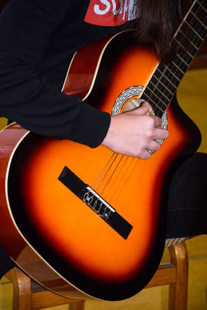 Acoustic guitar in hands of guitar player close up. Young guitarist, girl musician performing song....