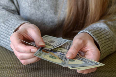 Dollar banknotes in female hands. Woman's hands counting money, currency of United States. Close-up. Selective focus. Copy space.の写真素材