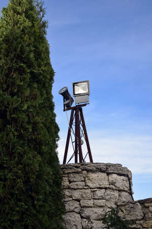 Fragment of stone building with lighting devices against blue cloudy sky. Copy space. Selective focus. Vertical photo.の写真素材