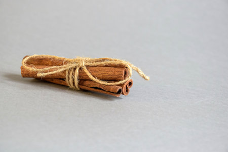 Cinnamon sticks tied with twine on gray background. Natural Light. Side view. Selective focus. Copy...