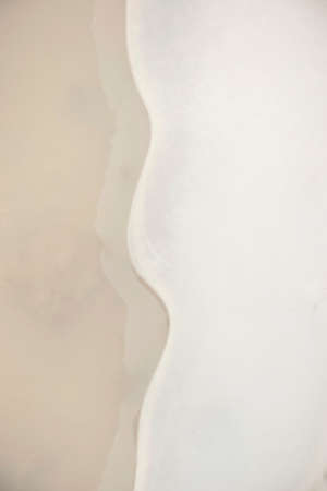 First ice covered puddle on country road. Abstract pattern on ice surface. Close-up. Top view....