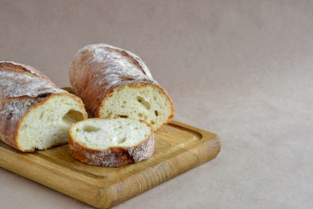 Bread loaf, cut into pieces, on wooden cutting board. Fresh baked bread on craft paper, home baked...