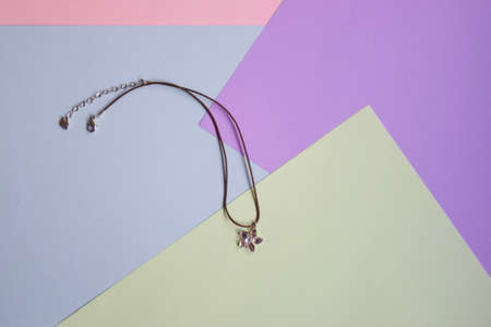 Pendant in shape of heart flower of glass on abstract multicolored paper background. Fashion women's jewelry. Top view. Copy space.の写真素材