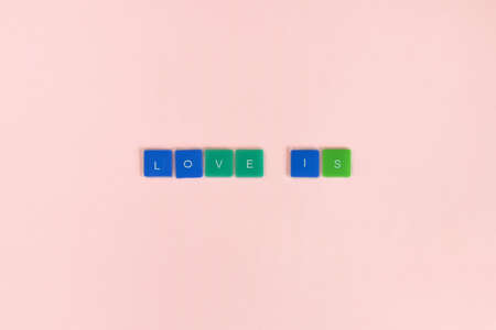 Love is - words made from colored letters on pink background. Top view. Copy space. Selective focus.の写真素材