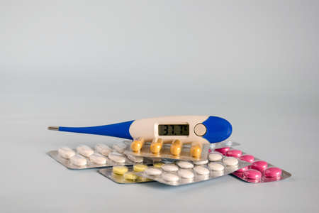 Different - tablets and pills in blister pack, medications drugs and electronic medicines thermometer shows elevated temperature - sign of illness. Close-up. Copy space. Selective focus.の写真素材