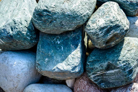 Background is made of natural stones of different colors and sizes. Natural texture. Turquoise rounded stones of sedimentary rocks. Horizontal photo. Top view. Close-up. Selective focus.の写真素材