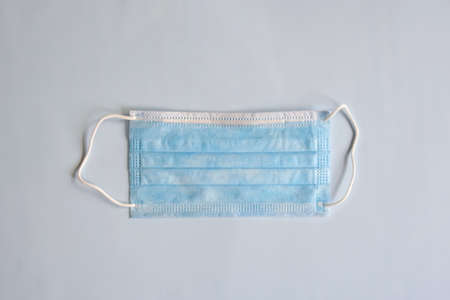 One disposable medical mask on light background. Virus protection remedies. Top view. Close-up....