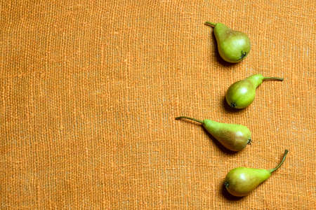 Four fresh ripe whole pears are lying on orange burlap. Top view. Close-up. Copy space. Healthy food, diet. Selective focus.の写真素材
