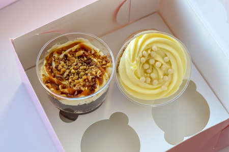 Delicate sweet desserts made of sponge dough and custard . Delicious desserts in transparent glasses of British cuisine in paper box. Close-up. Top view. Copy space. Selective focus.の写真素材