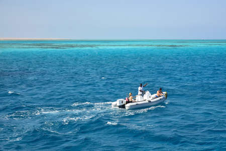 Tourists with instructor ride motor boat on Red Sea on sunny day. Coral reefs are visible in distance. Vacation in Egypt, holidays, resort, leisure and adventure, travel. Hurghada, Egypt -October 2021のeditorial素材