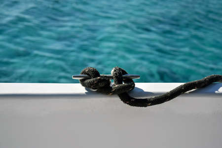 Close-up view nautical rope secured on cleat against blue sea. Rope is fixed to side of yacht. Copy space. Selective focus.の写真素材