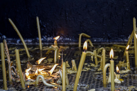 Burning candles in church. Burning candles shining in dark background. copyspace. Shallow depth of field.の写真素材