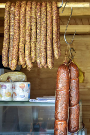 Sausage and others meat smoked delicacies of different colors and sizes are stacked on counter. Fair trade in homemade meat delicacies. close-up. selective focus.の写真素材