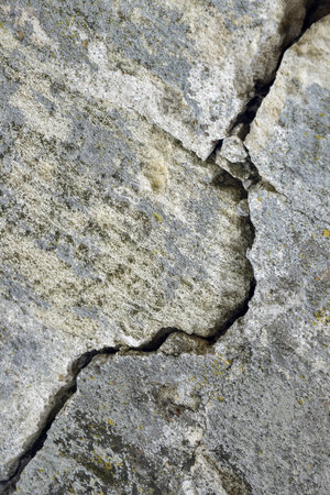 Big deep crack on wall with remnants of old plaster, abstract image of diagonal cleft. close-up. vertical photo. copyspace. selective focus.の写真素材