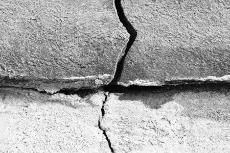 Big crack on gray wall, abstract image of vertical cleft. black and white photo. close-up. copyspace. selective focus.の写真素材