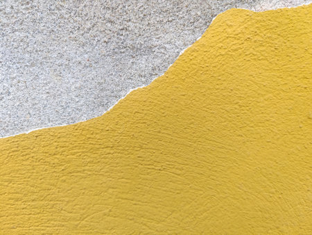 Background of old yellow wall with collapsed plaster. Texture of shabby weathered building surface. Destroyed wall with fallen plaster. copyspace. selective focus.の写真素材