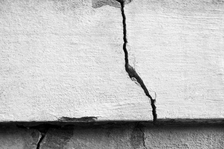 Big crack on old plastering wall. Long winding crack in cement surface of an old building. black and...
