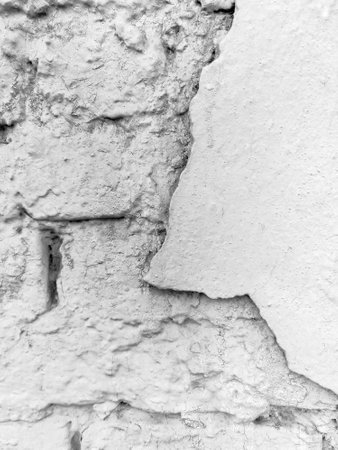 Surface of plastered brick wall of old building with cracks and crumbling plaster as background. copyspace. black and white photo. selective focus.の写真素材