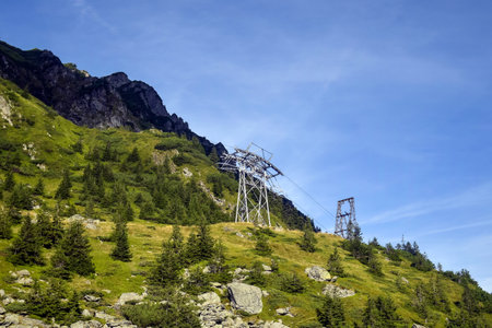The ski lift ascending steep side of mountain, transporting skiers and snowboarders to mountains...