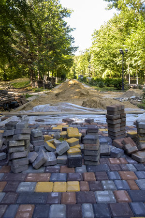 Process of laying multi-colored paving slabs on park alley on warm summer sunny day fills the atmosphere with life and joy. Close-up. Copy space for text.の写真素材