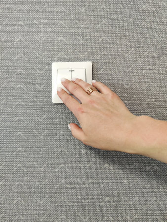 Turning light on/off. Woman pressing light switch on patterned wall, close-upの写真素材