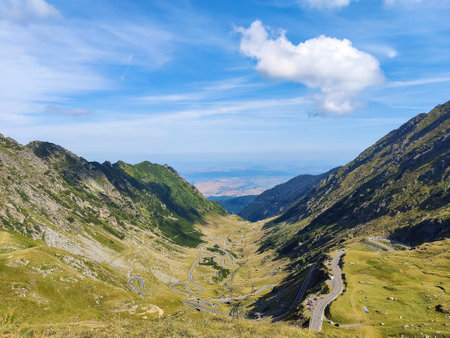 Mountain spring landscape against blue sky with white clouds. Romanian high mountain highway Transfegares. Green slopes of mountains.の写真素材
