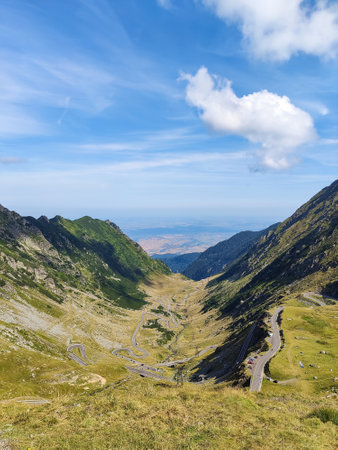 Mountain spring landscape against blue sky with white clouds. Romanian high mountain highway Transfegares. Green slopes of mountains.の写真素材