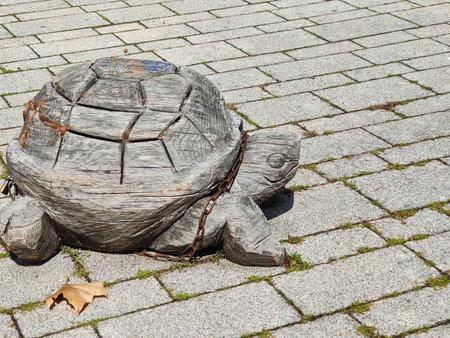 Small carved from wooden street sculpture of turtle, located on gray paving slabs. Handcrafted,...