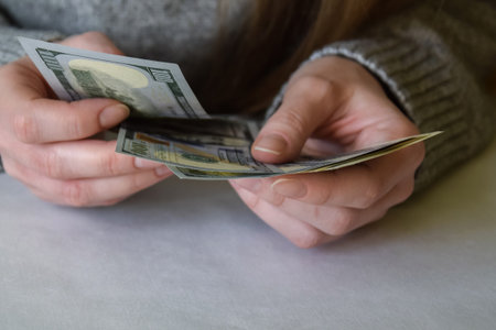 Dollars banknotes in female hands. Woman counting money, currency of United States. Close-up. Selective focus. Copy space.の写真素材