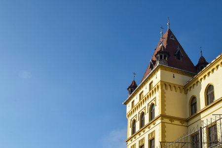 Old building castle with red tiled roof and towers in Gothic style in medieval European town. Clear blue sky. Copy space.の写真素材