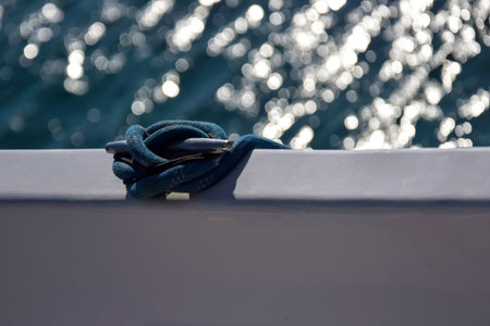 Close-up view of nautical rope secured on cleat against blue sea. Rope is fixed to the side of yacht. Copy space. Selective focus.の写真素材