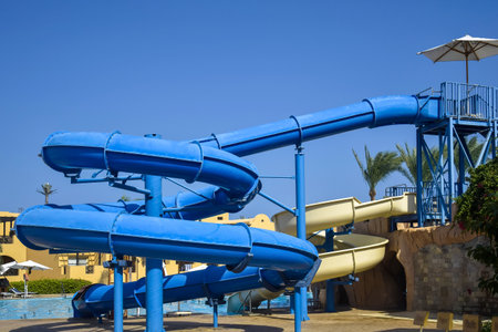 Water attraction, spiral slides in courtyard of cozy Egyptian hotel with palms. Transparent clean...