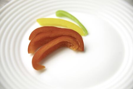 Bulgarian red green yellow pepper slices on white plateの写真素材