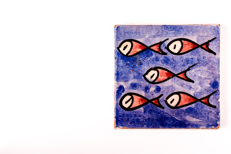 blue tile with a group of five red fishes drawing on it. over white with copy space for the menu on the leftの写真素材