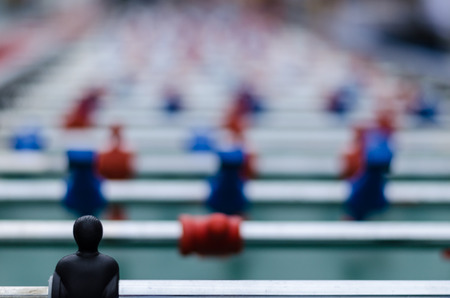 the goal keeper of a soccer table n front of the other plastic figure in red and blue
