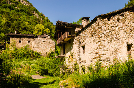 a group of house abandoned and damage in the middle of italian alps, summer. Italy.