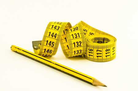 still life with a yellow tape measure and a pencil, over white