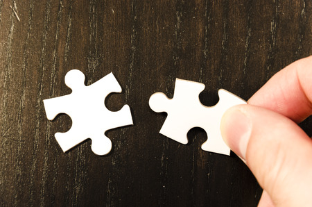 the first choice of a white jigsaw/puzzle, over  black wooden table background, symbol of problem solvingの写真素材