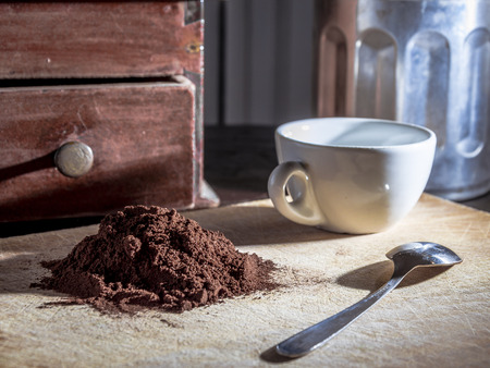 still life with a white cup and steel little spoon beside a pile of coffe powderの写真素材
